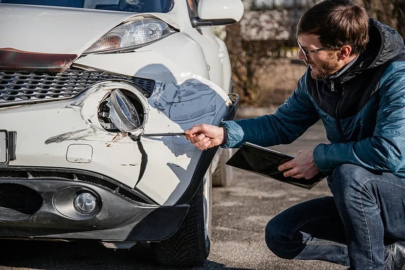 A damaged front bumper being inspected