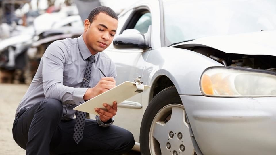 An adjuster documenting damage on a vehicle