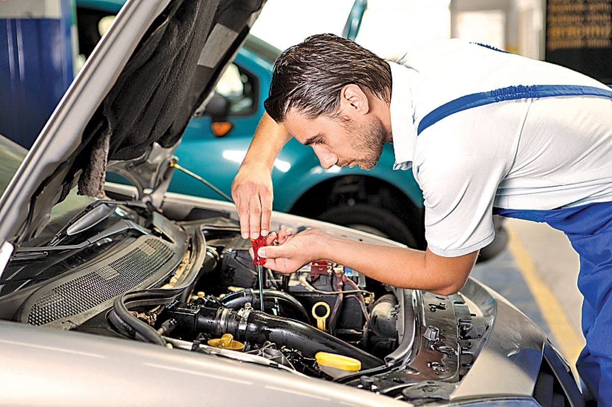 A technician working inside an engine bay